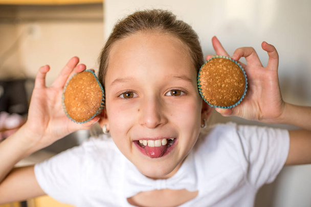 girl holding cupcakes in kitchen - Zdjęcie, obraz