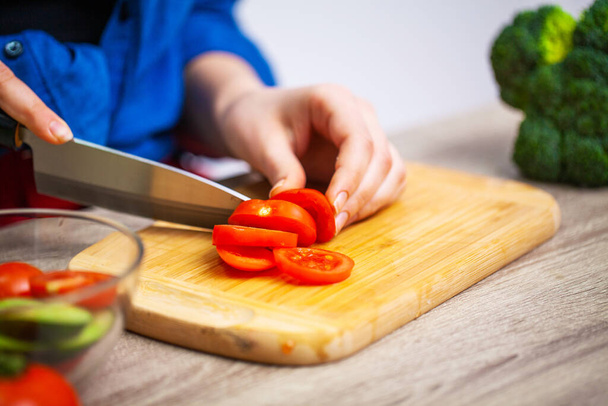 Closeup of woman slices tomato for diet salad - Photo, Image