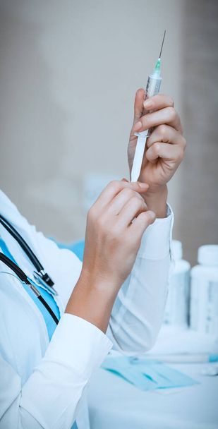 Closeup photo of a nurse's hands holding a syringe, vaccination cure, medical support, anti-virus injection, medical treatment - Foto, Imagem