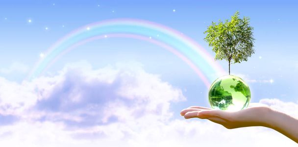 世界地球の日のカード。植林木、オゾンデーの概念。環境を保全し、緑の惑星と生態系を保存し、保護する。地球の地球と星の空と虹の背景に手で木を育てる. - 写真・画像