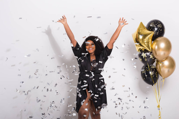 Party, ünnepek és születésnapi koncepció - Ünnepi boldogság, fiatal nő táncol nagy mosollyal dobott konfetti - Fotó, kép