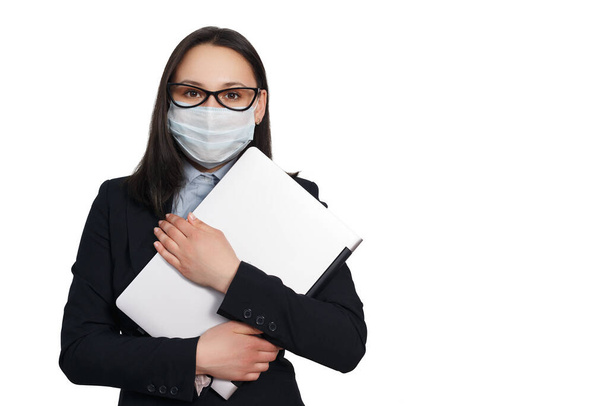 portrait of a woman in a medical protective mask, in a blouse and jacket, with a laptop in her hands. isolated on a white background - 写真・画像