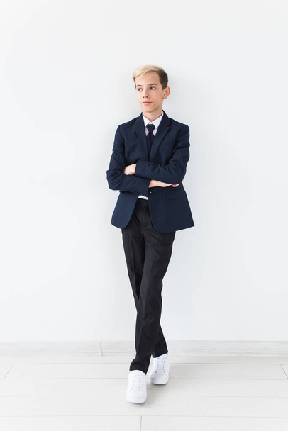 Portrait of stylish school boy teenager in white shirt and jacket against white background. - 写真・画像