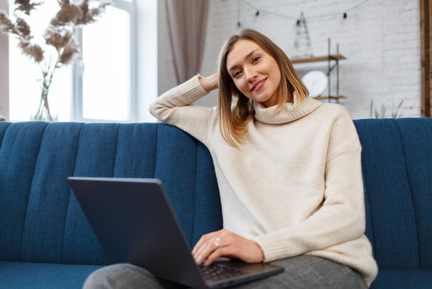 Working from home.Communication online with colleagues and freelancers.Portrait of young female freelancer using laptop and smiling. Concept of young people working with mobile devices - Fotoğraf, Görsel
