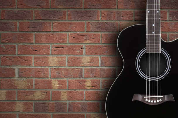 Черная акустическая гитара на фоне брика с пространством для копирования
 - Фото, изображение