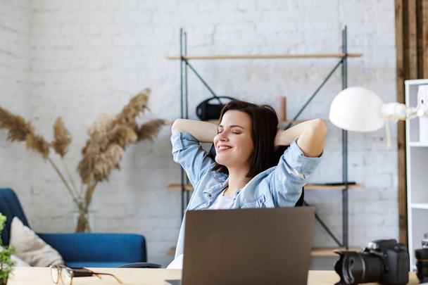 Werken vanuit huis. Portret van lachende vrouwelijke freelancer met laptop. Ontspanning na het verkrijgen van goede resultaten op het werk. Concept van jongeren die werken met mobiele apparaten - Foto, afbeelding