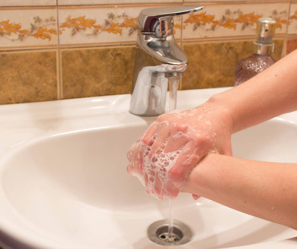 κορίτσι πλένει τα χέρια με σαπούνι πάνω από το νεροχύτη στο μπάνιο - Φωτογραφία, εικόνα