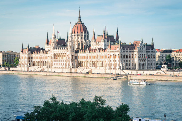 日没時のブダペスト議会。ハンガリーのドナウ川を渡る船 - 写真・画像
