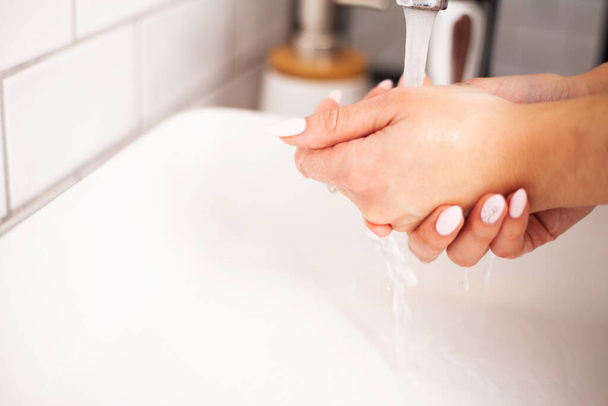 A nő kezet mos egy fényes fürdőszobában. - Fotó, kép