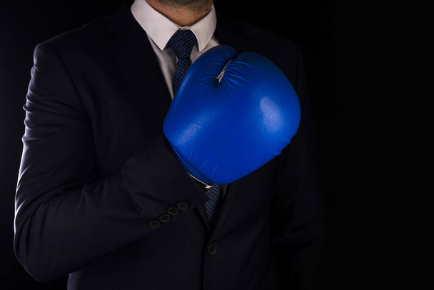 Businessman in blue boxing gloves on a dark background. - Foto, imagen