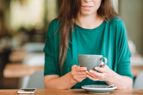 Όμορφη γυναίκα τρώει πρωινό σε υπαίθριο καφέ. Ευτυχισμένη νεαρή γυναίκα που πίνει καφέ. - Φωτογραφία, εικόνα