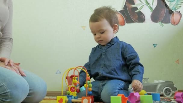 A child plays with mom toys sitting on the floor - Materiał filmowy, wideo