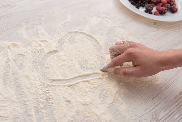 女性の手は小麦粉に心を描き - 写真・画像