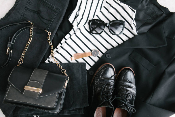 overhead flat lay vista mulher roupas preto e branco bolsa jeans blazer sapatos óculos de sol
 - Foto, Imagem