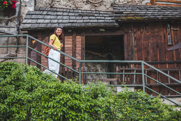 joven bastante sonriente turista mujer caminando por pequeñas escaleras de la calle hallstatt. vacaciones de verano - Foto, imagen