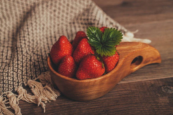 Fresh strawberries with leaves in wooden bowl on rustic brown wooden background - Fotografie, Obrázek