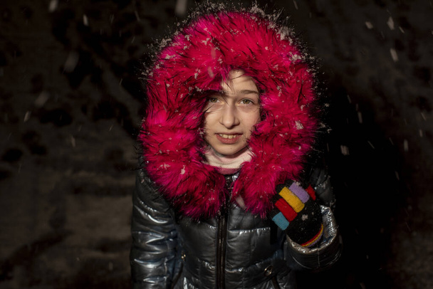 Portret pięknej dziewięcioletniej dziewczynki. 9-letnia dziewczyna w niebieskiej kurtce. Uczennica w zimie. Nastolatka. Zima i śnieg. Śnieżny wieczór. Dziecko lubi śnieg. Kurtka z eko-futrem - Zdjęcie, obraz