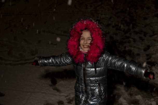 Portret pięknej dziewięcioletniej dziewczynki. 9-letnia dziewczyna w niebieskiej kurtce. Uczennica w zimie. Nastolatka. Zima i śnieg. Śnieżny wieczór. Dziecko lubi śnieg. Kurtka z eko-futrem - Zdjęcie, obraz