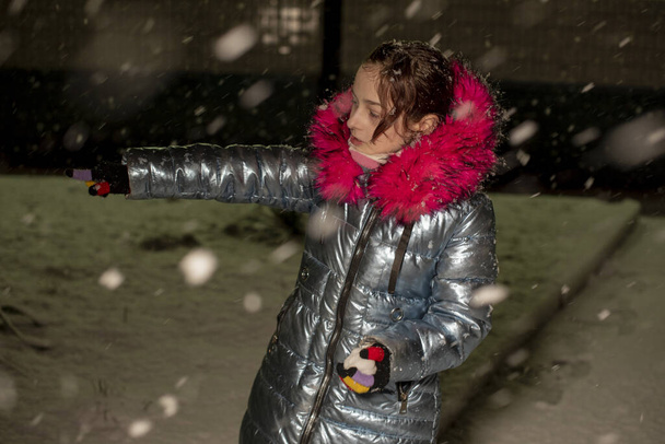 portré egy gyönyörű 9 éves kislányról. 9 éves lány kék kabátban. Iskolásgyerek télen. Tinédzser. Tél és hó. Havas este. A gyermek élvezi a havat. ökoprémes kabát - Fotó, kép