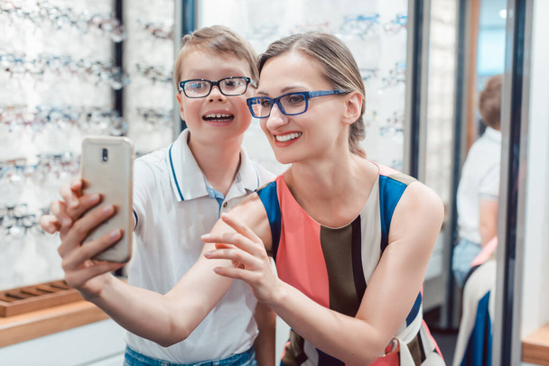 Matka i syn biorąc selfie z nowe okulary okulista sklep - Zdjęcie, obraz