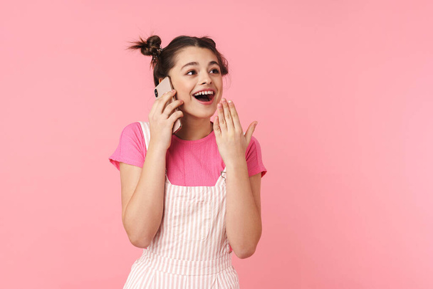 Photo of excited nice girl with nose ring talking on cellphone and expressing surprise isolated over pink background - Valokuva, kuva