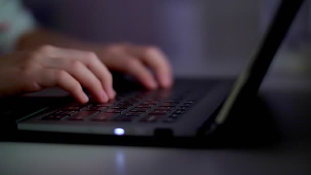 close-up, handen van een meisje, een kind typen op een laptop toetsenbord, onder het licht van de monitor, 's nachts. - Video