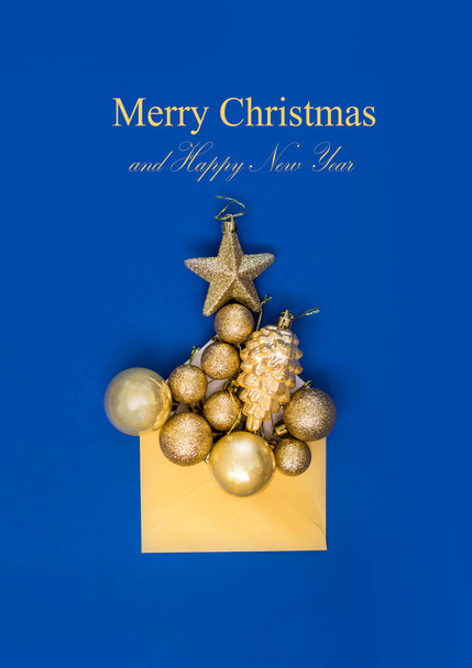 On a blue background a yellow envelope with gold Christmas trees and a star. Holiday content - Foto, afbeelding