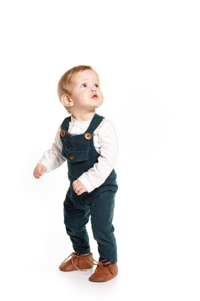 A one-year-old boy in a green jumpsuit on a white background - Foto, imagen