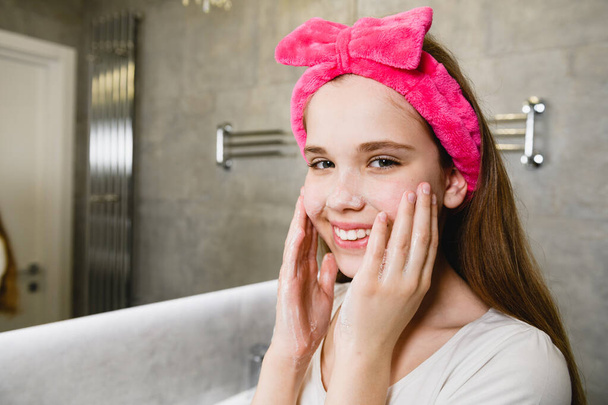 Teen girl wash face with soap foam - 写真・画像
