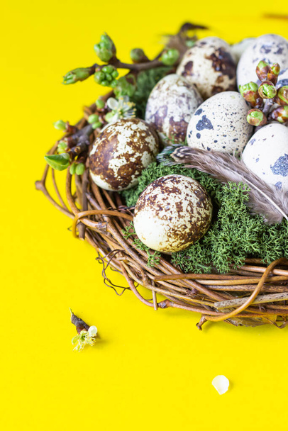 Small bird nest with quail eggs on yellow paper background. Cute Easter greeting card. Spring and Easter holiday concept with copy space. Flat lay composition. - Foto, Imagen