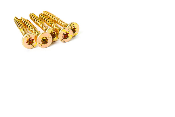 Gold screws scattered randomly on a white background. Torx yellow zinc head screws - Photo, Image
