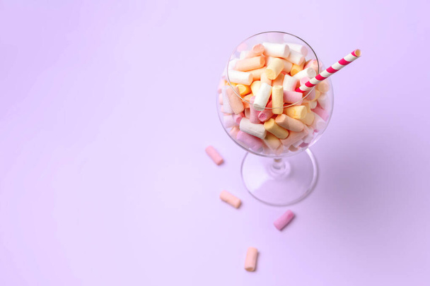 Μίνι marshmallows σε ένα ποτήρι σε ανοιχτό μωβ φόντο. Πολύχρωμα ζαχαρωτά σε ποτήρι. Η ιδέα της Ζαχαροπλαστικής. Αντιγραφή κοντινού χώρου - Φωτογραφία, εικόνα