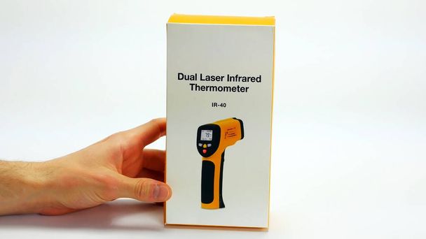 Man hand Holding closed box package for infrared thermometer. Isolated on white background. - Photo, Image