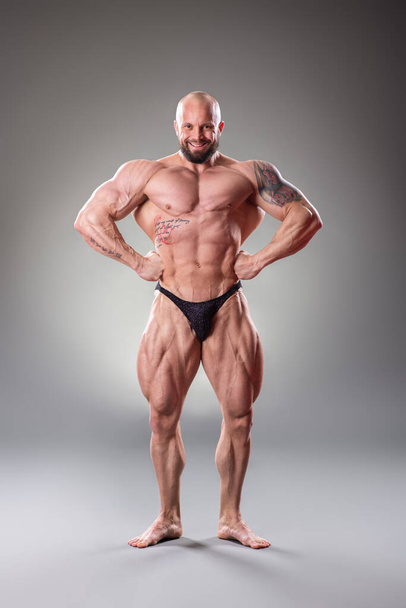 Sexy muscular bodybuider posing on the gray background - Fotoğraf, Görsel