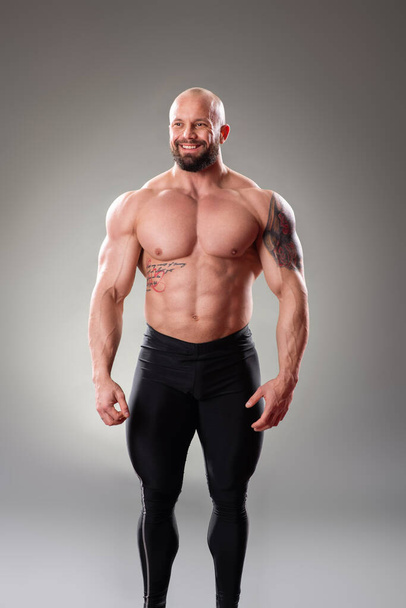 Sexy muscular bodybuider posing on the gray background - Foto, Imagen