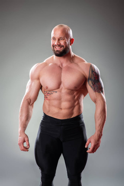 Sexy muscular bodybuider posing on the gray background - Φωτογραφία, εικόνα