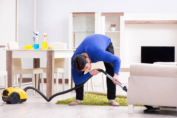 Joven hombre aspiradora limpieza de su apartamento - Foto, Imagen