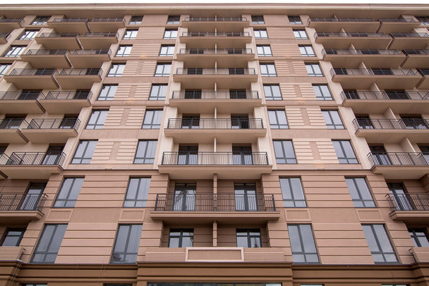 la fachada del edificio de varios pisos es de color marrón con ventanas de marco negro y elementos arquitectónicos de moldeo y oxidación, de cerca
. - Foto, Imagen
