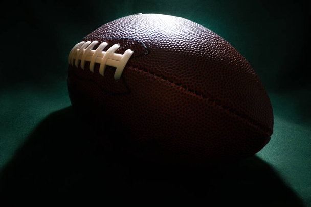 Stimmungsvolle Beleuchtung und extreme Weitwinkel-Makro-Nahaufnahme an den Schnürsenkeln, der strukturierten Haut und den Grübchen eines American Football. - Foto, Bild