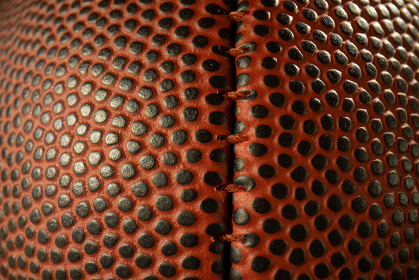 Football Macro Stitching. Extreme wide angle macro close-up on the center stitching and textured dimples of an American football. - Photo, Image