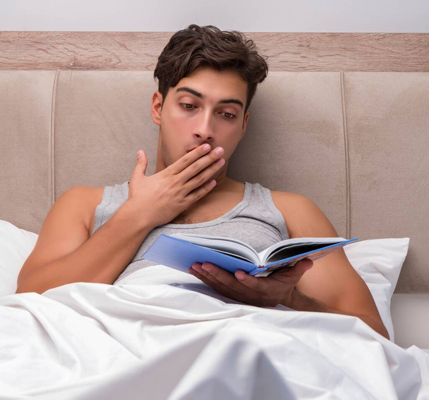 Ανάγνωση βιβλίων άνδρα στο κρεβάτι - Φωτογραφία, εικόνα
