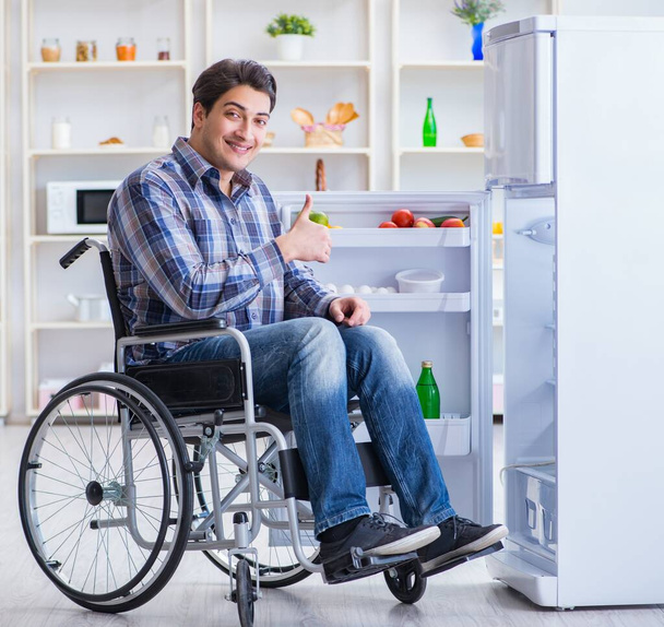 Jovem deficiente ferido homem abrindo a porta do frigorífico - Foto, Imagem