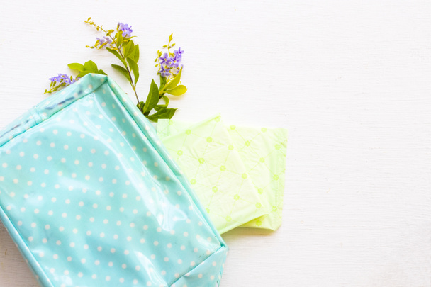 sanitaire handdoek gezondheidszorg persoonlijk gebruik van de vrouw met paarse bloemen in blauwe zak arrangement platte lay stijl op de achtergrond wit - Foto, afbeelding
