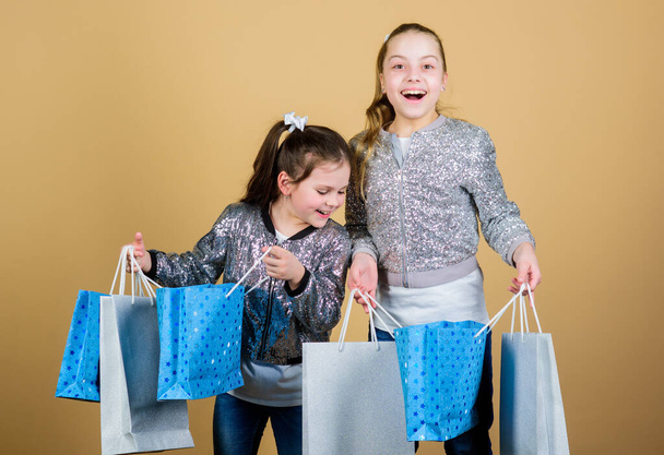 Shopping day. Children hold bunch packages. Kids fashion. Expect more. Pay less. Girls sisters friends with shopping bags beige background. Shopping and purchase. Black friday. Sale and discount - Zdjęcie, obraz
