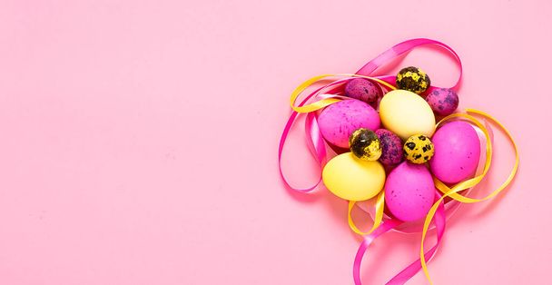 Frohe Ostern. Farbige Eier auf rosa Hintergrund. Leerraum flaches Layout kopieren. Banner mit Platz für Werbung. - Foto, Bild
