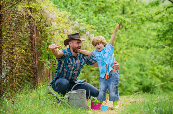 Dad teaching little son care plants. Personal example. Spring garden. Little helper in garden. Planting flowers. Growing plants. Take care of plants. Boy and father in nature with watering can - Fotoğraf, Görsel