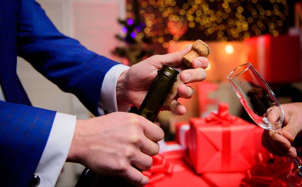 Celebrate new year with champagne. Hands opening champagne bottle and hold glass christmas decorations background. Cheers concept. Last minute before new year. Drink champagne or sparkling wine - Photo, Image