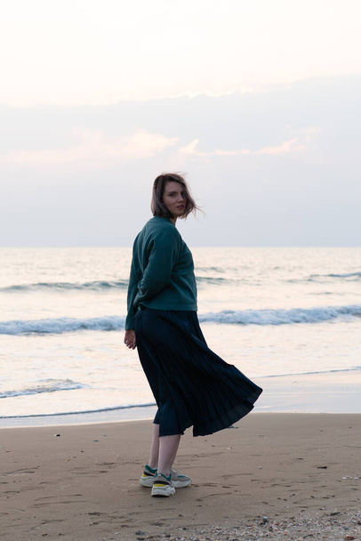 ragazza si trova sulla riva del mare in un maglione
 - Foto, immagini