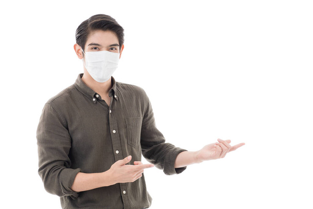 Азиатский мужчина в хирургической защитной маске позирует в стиле жеста рекламной модели как подарок или представить продукты, услуги и товары. Изолированный на белом фоне с копировальным пространством
. - Фото, изображение