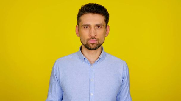 Confident bearded man in a blue shirt on a yellow background - Photo, Image